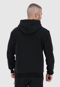 Felpa nera in cotone con cappuccio ampio, polsini e orlo inferiore a costine. Design semplice, texture liscia e senza motivi o accenti visibili.