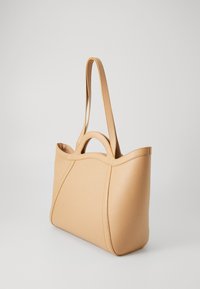 Beige leather tote bag with a smooth texture, rounded handles, and gentle curves in design. Features two long straps for shoulder carry.