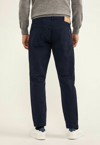 Pantalones de algodón azul marino con un diseño de pierna recta, que cuentan con dos bolsillos traseros y un parche de cuero en la cinturilla.