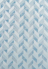 Tessuto tessile che presenta un motivo geometrico a spina di pesce in diverse tonalità di blu e azzurro, con una superficie strutturata e un design intrecciato.