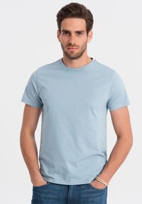 Lyseblå kortærmet t-shirt i glat bomuldsstof, med rund halsudskæring og en afslappet pasform, parret med denim jeans.