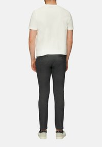 Witte T-shirt met korte mouwen, gecombineerd met donkergrijze slim-fit broek en lichte sneakers, met een strakke, minimalistische uitstraling.