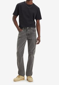 Svart t-shirt med kort ärm kombinerad med grå denimjeans. Denimen har en urtvättad look och raka ben. Bruna mockaskor fulländar stilen.