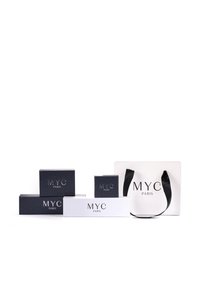 Collezione di imballaggi composta da due scatole nere e due scatole bianche, tutte con la scritta "MYC PARIS" in rilievo. Include una borsa da shopping bianca con manici neri.