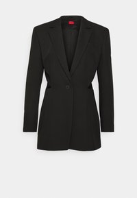 Blazer nero su misura con maniche lunghe, chiusura a un pulsante, revers a specchio e dettagli a taglio laterale. Tessuto liscio con fodera testurizzata.