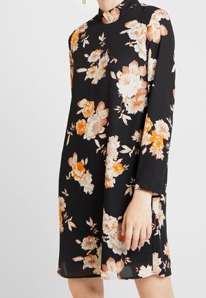 Robe noire à manches longues avec un col haut présentant de grands motifs floraux dans des tons de blanc, orange et beige.