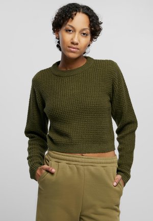 Un pull court vert olive avec une texture côtelée et des manches longues, associé à un pantalon de jogging marron clair à cordon de serrage avec des poches latérales.