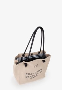 Borsa tote in tela di colore beige chiaro con manici neri, caratterizzata da un logo stampato e un interno a righe. Parte superiore aperta con chiusura a coulisse.