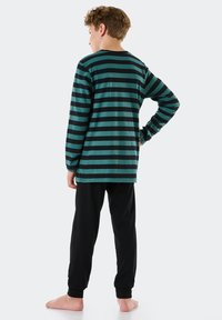 Camicia a maniche lunghe a righe verde scuro e nere, abbinata a pantaloni neri. Materiale in cotone, vestibilità comoda e polsini elastici sui pantaloni.