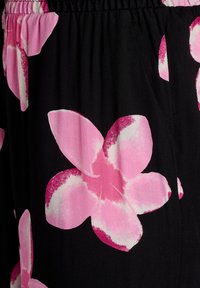 Tessuto nero con grandi motivi floreali rosa e dettagli bianchi. La texture appare morbida, con un dettaglio di vita elastica.