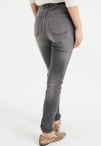 Gray denim jeans with a slim fit, mid-rise waist, and back pockets. Rolled cuffs and slight fading detail. Worn with patterned flats.
