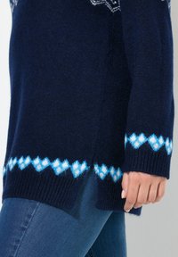 Marinblå stickad tröja med ett vitt och ljusblått diamantmönster vid fållen och ärmsluten; ribbad textur; sidoklyftor för passform.