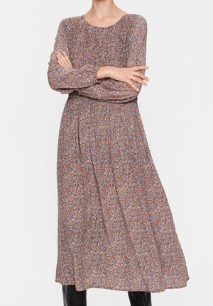Brązowa sukienka midi w kwiaty z długimi rękawami, marszczonym dekoltem i elastycznym pasem. Zdobiona małymi niebieskimi i pomarańczowymi kwiatami na teksturowanej tkaninie.