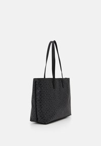 Sac fourre-tout noir en tissu résistant, arborant un motif logo sur toute sa surface, avec deux longues poignées et un design rectangulaire structuré.