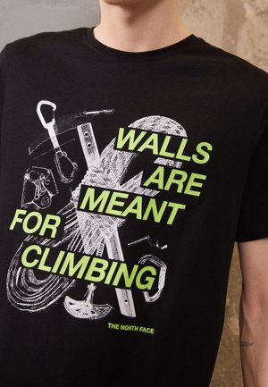 Schwarzes T-Shirt mit weißem und neongrünem Text, auf dem steht: "WÄNDE SIND DA, UMEBEN ZU WERDEN." Enthält Grafiken von Kletterausrüstung.