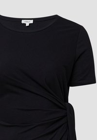 Schwarzes T-Shirt aus weichem Stoff, mit kurzen Ärmeln, rundem Halsausschnitt und einem gerafften seitlichen Detail für eine figurbetonte Optik.