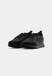 Pair of black low-top sneakers with laces and red "HUGO" logo on side, shown against plain white background.