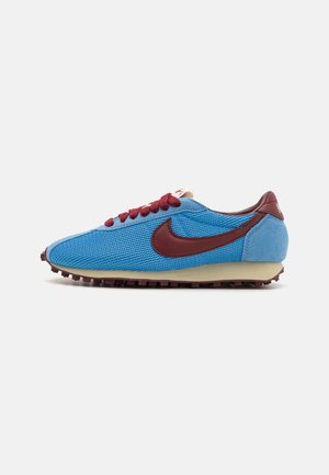 Zapatillas de malla azul y ante con acentos y cordones en color burdeos. Presenta un upper texturizado y una suela de goma crema con pequeñas tachuelas.