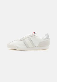 Zapatillas blancas con tejido de malla, una capa de cuero suave y acentos de ante. Incluyen rayas tonal y una suela de goma texturizada.