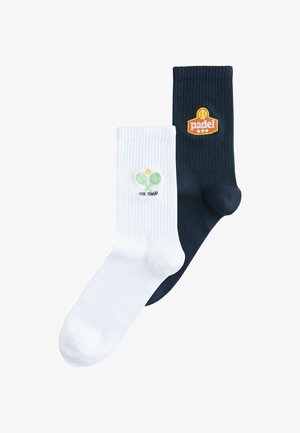 Paar gerippte Socken, eines weiß mit grünem Tennis-Schläger- und Ball-Stickerei, eines schwarz mit orangefarbenem "Padel"- und Ball-Emblem.