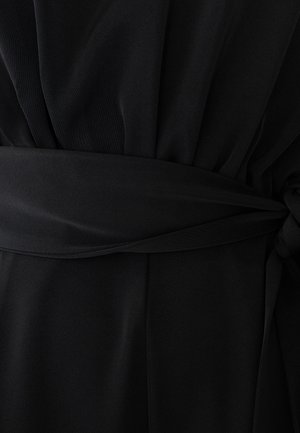 Mustmust riiet laia vööga, mis on sõlmida tõmmatud puusakohale, näidates koondatud kangast vöö kohal ja siledat kangast vöö all.