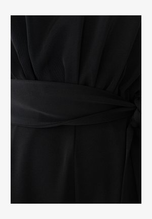 Musta kangasmekko, jossa on leveä vyö solmittuna solmuun vyötäröllä, näyttäen rypistyneen kankaan vyön yläpuolella ja sileän kankaan vyön alapuolella.