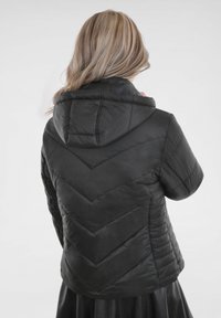 Schwarze gesteppten Pufferjacke mit einem Chevron-Muster, Kapuze und kurzen Ärmeln, mit glatter Textur und Nähdetails.