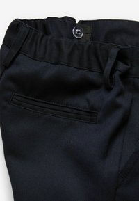 Pantaloni blu navy con una texture liscia, cintura elastica e una tasca posteriore. Presentano una chiusura con bottone e passanti per cintura.