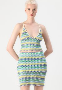 Kötött crop top és mini szoknya szett, élénk sárga, zöld, kék és lila hullámos mintákkal. Állítható pántokkal és texturált felülettel.