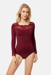 Top burdeos de manga larga con detalles de encaje en el escote y los puños, con un diseño ajustado y una textura suave. Combinado con pantalones a juego.
