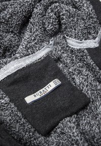 Telón de forro gris con una superficie texturizada, que presenta un panel gris oscuro y una etiqueta que dice "BURATTI SPORT" en azul y blanco.