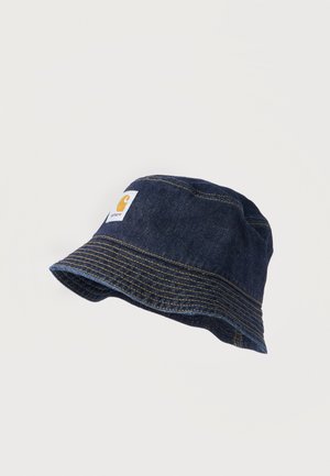 Mørkeblå denim-bøttehat med gule kontrastsømme og et firkantet hvidt mærke med en gul logo foran.