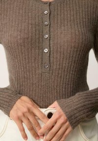 Brązowy sweter z ribbowanym splotem z okrągłym dekoltem i sześcioma guzikami, z długimi rękawami i teksturowanym materiałem.