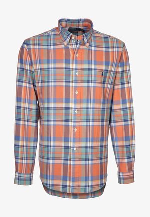 Chemise à manches longues boutonnée avec motif à carreaux orange, bleu, vert et marron, avec col et petit logo brodé sur la poitrine.