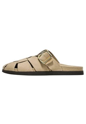 Bež semiš natikač z odprto peto, več trakovi in veliko zlato sponko na ravnem črnem podplatu.