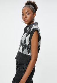 Gebreide sweater vest in zwart en lichtgrijs met een ruitpatroon, korte mouwen en een kraag. Ribgebreide zoom op de taille.