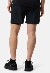 Mustat urheilushortsit, joissa on sileä pinta ja sisäkerros, joka on tiukka. Yhdistetty mustiin, nauhoilla sidottuihin juoksukengiin, joissa on verkkomateriaalia.