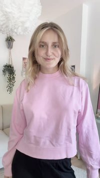 Světle růžový zkrácený sweatshirt s dlouhými rukávy a kulatým výstřihem. Měkká tkanina, minimální švy, ribbené manžety a lem.