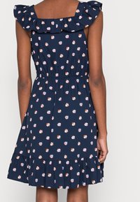 Náměsíčná květinová šaty s ruffled ramínky, nařaseným pasem a rozšířenou sukní. Obsahuje barevné malé květiny a vrstvený lem.