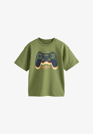 Tricou verde măsliniu cu mâneci scurte, cu o grafică albastru închis a unui controler de joc și textul „GAMER” și „LEVEL UP Player One Ready” pe față.