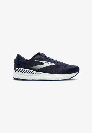 Tumesinine jooksujalats, millel on hingav võrgust pealsed, ümar varvas, valge vahevaip ja sinine kummist tall. Selles on Brooks'i logo ja detail "BEAST GTS".