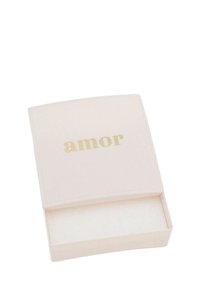 Liten, fyrkantig, off-white låda med ett glidlock som är delvis öppet, med ordet "amor" i guldbokstäver på locket.