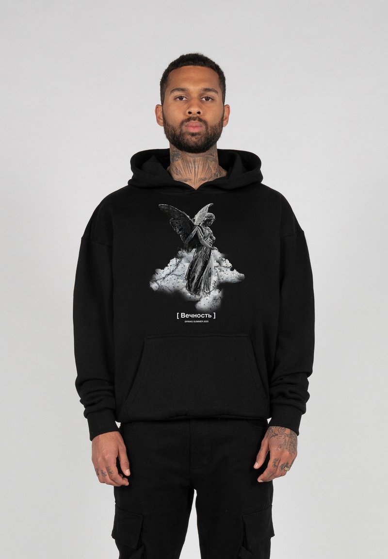 Schwarzer Hoodie mit einem grauen Grafikmotiv eines geflügelten Wesens auf einer Wolke, mit weißem Text unter dem Bild. Aus weichem Stoff mit relaxed Fit.
