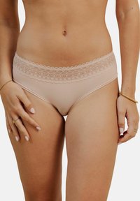 Sous-vêtements pour femmes de couleur rose clair avec une taille en dentelle texturée et un corps lisse, conçus pour le confort et une silhouette ajustée.
