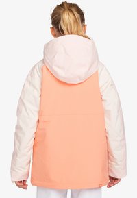 Färgblockerad jacka med en korallfärgad rygg, vita ärmar och en rosa huva. Har en avslappnad passform, vattentätt material och justerbara ärmslut.