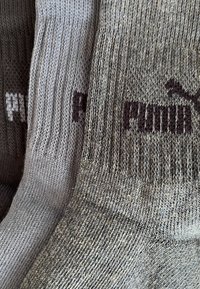 Puma socks in light gray and dark gray. Ribbed texture with a woven logo. Soft, elastic fabric; features contrasting colors and designs.