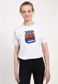 Bílý bavlněný tričko s barevným grafikou šesti skleněných lahví sody a modrým boxem označeným "PEPSI" na spodní straně.