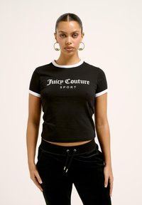 Černé zkrácené tričko s bílým lemem, s výrazným logem "Juicy Couture SPORT". V kombinaci s černými sametovými tepláky a zlatými akcenty.