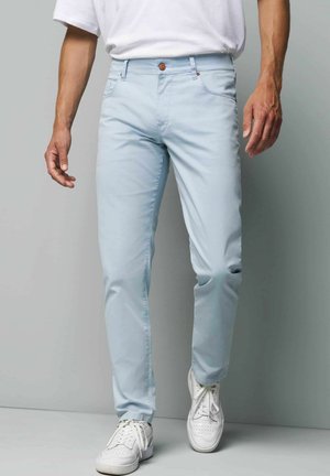 Hellblaue Chinos aus einem Baumwollmix, mit schmalem Schnitt, Fünf-Taschen-Design und Knopfverschluss, kombiniert mit weißen Sneakern.