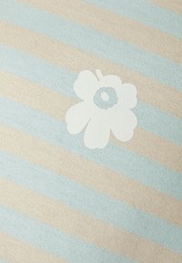 Bomullstyg med vertikala ljusblå och beige ränder och ett framträdande vitt blommönster i mitten. Slät textur.